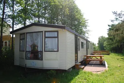 a small white caravan in a field with a picnic table at Anser Collis in Wadowice