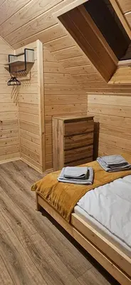 a bedroom with a bed in a wooden cabin at Domek Pod Skarpą in Wieprzec