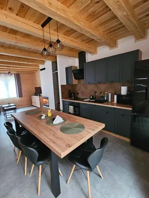 a kitchen with a wooden table and black chairs at Domek Pod Skarpą in Wieprzec
