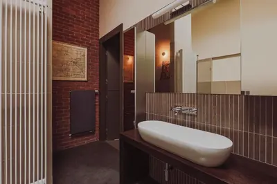 a bathroom with a white sink and a brick wall at SAW! KRAKÓW Apartments - Studencka in Kraków