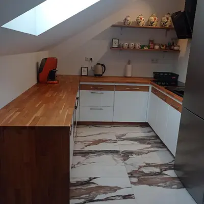 a kitchen with white cabinets and a marble floor at U Tofika in Grzechynia
