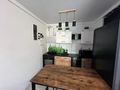 a kitchen with a wooden table and a black refrigerator at Apartament Bastian Złocień Kraków in Kraków