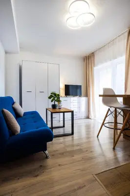 a living room with a blue couch and a table at Aleja 69 Balcony in Kraków