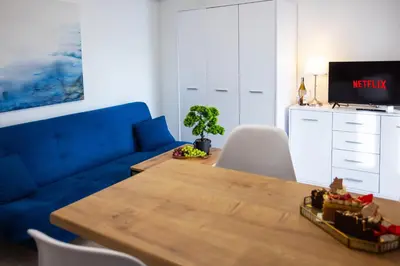 a living room with a blue couch and a wooden table at Aleja 69 Balcony in Kraków