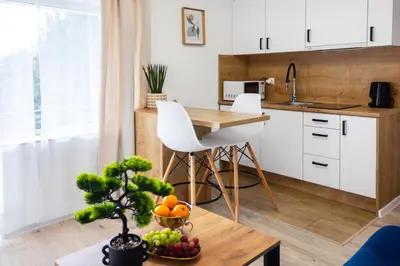a kitchen with white cabinets and a table with fruit on a table at Aleja 69 Balcony in Kraków