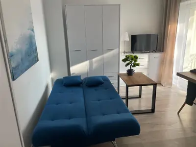 a blue couch in a living room with a table at Aleja 69 Balcony in Kraków