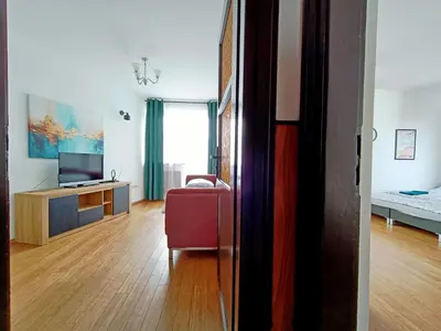 a living room with a red chair and a television at pokoje przytulnie jak w domu in Kraków