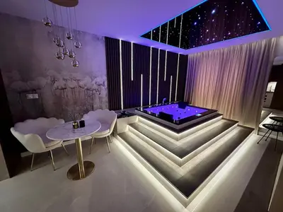 a room with a tub with a table and chairs at Masarska 8 VIP Apartamenty JACUZZI in Kraków