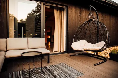 a swing on a porch with a couch and a table at Stodoła Na Kamionce in Kwaczała