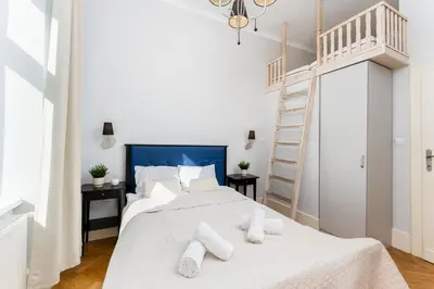a white bedroom with a white bed with white pillows at Tomasza Apartments by VSI in Kraków