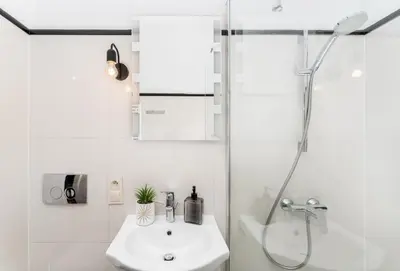 a white bathroom with a shower and a sink at Tomasza Apartments by VSI in Kraków