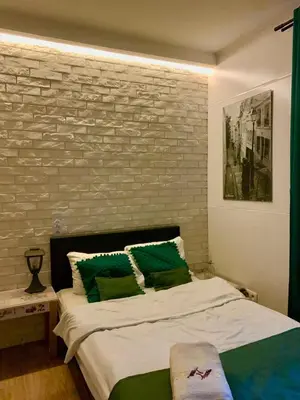 a bedroom with a bed with green pillows and a brick wall at Green Apartment Krakow in Kraków