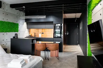 a kitchen with black cabinets and a counter with chairs at Wiślane Tarasy - UNIQUE Apartments 4YOU - 9 piętro z pięknym widokiem na centrum Krakowa in Kraków