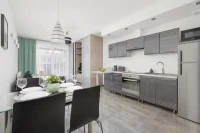 a kitchen and dining room with a table and chairs at Apartament w Spokojnej Okolicy z Parkingiem by Noclegi Renters in Kraków