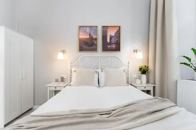 a white bedroom with a white bed and two tables at LORETO 1 by Cozyplace in Kraków