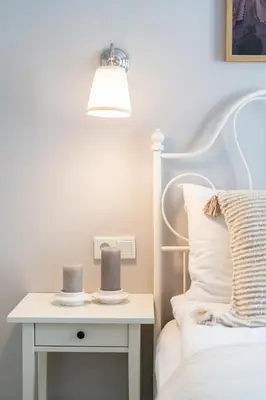 a bed with a white bedside table with two candles on it at LORETO 1 by Cozyplace in Kraków