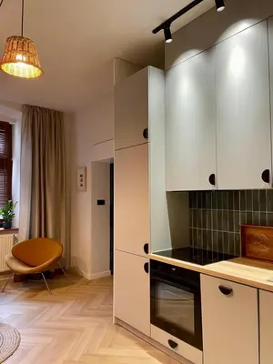 a kitchen with white cabinets and a table and a chair at Komfortowy apartament in Bochnia