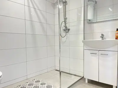 a white bathroom with a sink and a shower at Apartamenty Artur in Oświęcim