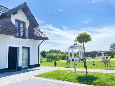 a white house with a palm tree and a gazebo at Apartamenty Artur in Oświęcim