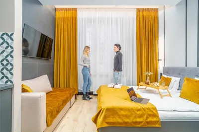 a man and woman standing in a bedroom looking out the window at Platinia Premium Apartments in Kraków