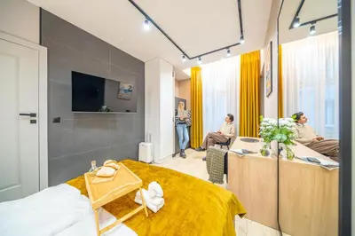 a room with a bed and a desk and people at Platinia Premium Apartments in Kraków