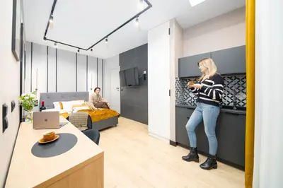 a woman standing in a bedroom with a man in a bed at Platinia Premium Apartments in Kraków