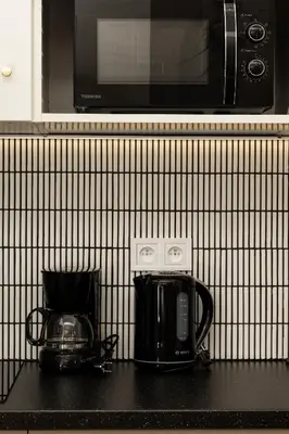 a black counter top with a microwave and a coffee maker at Comfort Central Studio - by Upstairs in Kraków