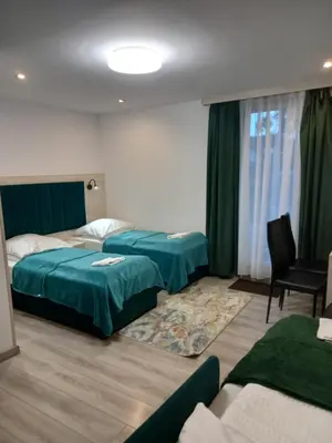 a hotel room with two beds and a chair at Komfortowe pokoje przy Szymonowica w Krakowie in Kraków