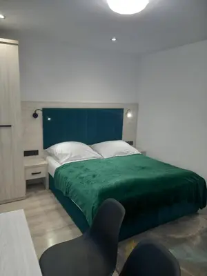 a bedroom with a green bed with a black chair at Komfortowe pokoje przy Szymonowica w Krakowie in Kraków