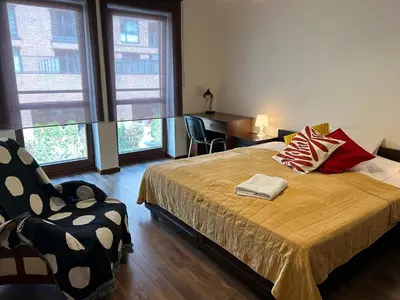 a bedroom with a bed and a chair and windows at Old Town Apartments - free parking Przemysłowa str in Kraków