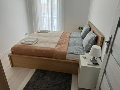 a bedroom with a bed and a night stand with a lamp at Luksusowy Apartament in Jaworzno