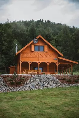a large wooden cabin with a stone wall at Chata Zawrot in Wytrzyszczka