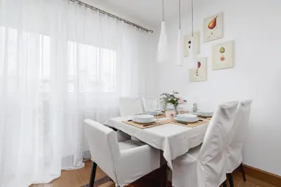 a white dining room with a table and white chairs at Cozy Apartment with Parking in Kraków by Noclegi Renters in Kraków