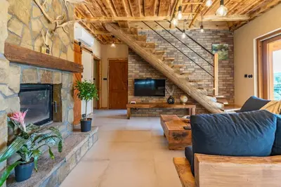 a living room with a stone fireplace and stairs at Dom 