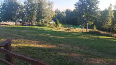 a large grassy field with a fence and a playground at Domki Pod Biegunem, Wioska Smerfów oraz Wzgórze Gargamela in Żywiec