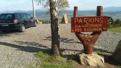 a sign sitting next to a tree on a gravel road at Domki Pod Biegunem, Wioska Smerfów oraz Wzgórze Gargamela in Żywiec