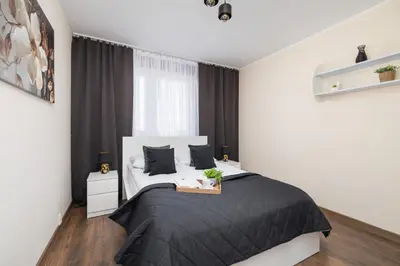 a bedroom with a black and white bed and a window at Przytulny Apartament z 3 sypialniami z Biurkiem do Pracy Zdalnej by Noclegi Renters in Kraków