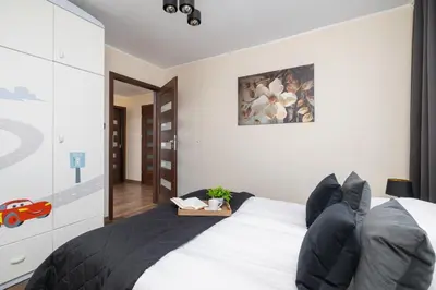 a bedroom with a white bed with black pillows at Przytulny Apartament z 3 sypialniami z Biurkiem do Pracy Zdalnej by Noclegi Renters in Kraków