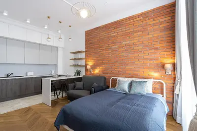 a bedroom with a bed and a brick wall at Studio apartment - Starowiślna 41 street in Kraków