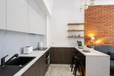 a kitchen with white counters and a brick wall at Studio apartment - Starowiślna 41 street in Kraków