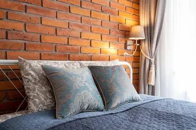 a bedroom with a brick wall and a bed with pillows at Studio apartment - Starowiślna 41 street in Kraków