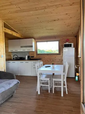 a kitchen and dining room with a white table and chairs at Domki- Limanowa domek 3 domek z jacuzzi i sauną in Limanowa