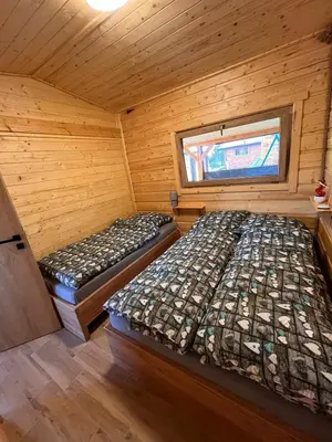 two beds in a wooden room with a window at Domki- Limanowa domek 3 domek z jacuzzi i sauną in Limanowa