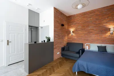 a bedroom with a brick wall and a bed and a chair at Apartment with balcony - Starowiślna 41 in Kraków