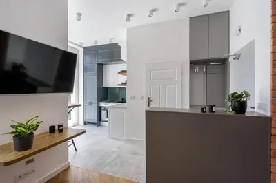 a kitchen with white cabinets and a flat screen tv at Apartment with balcony - Starowiślna 41 in Kraków