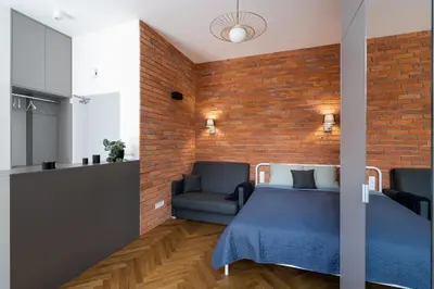 a bedroom with a bed and a brick wall at Apartment with balcony - Starowiślna 41 in Kraków