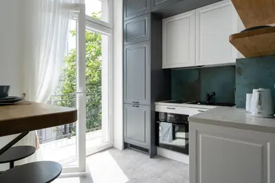 a kitchen with white cabinets and a large window at Apartment with balcony - Starowiślna 41 in Kraków