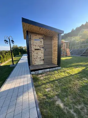 a small wooden building on a grass field at Domki- Limanowa domek 4 domek z jacuzzi i sauną in Limanowa