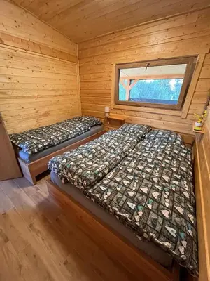 two beds in a log cabin with a window at Domki- Limanowa domek 4 domek z jacuzzi i sauną in Limanowa