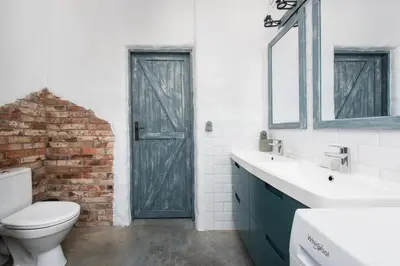 a bathroom with a white toilet and a brick wall at Yellow villa in Zator